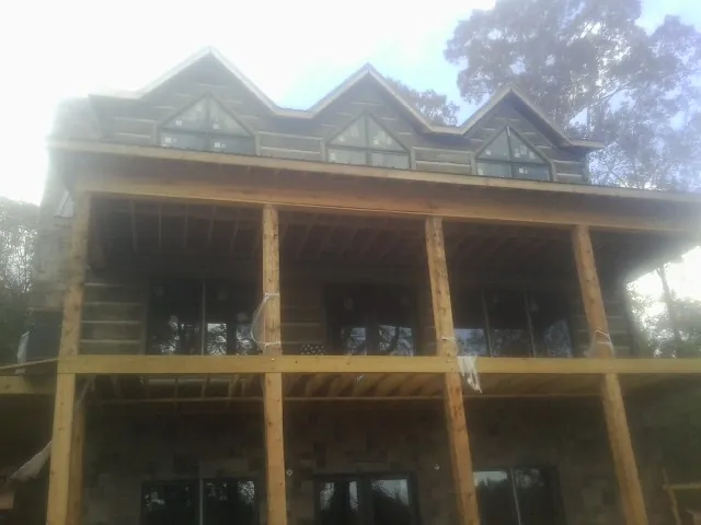 Dormers and porch framing on a large log home under construction — Roof Coating work by our crew in Concord
